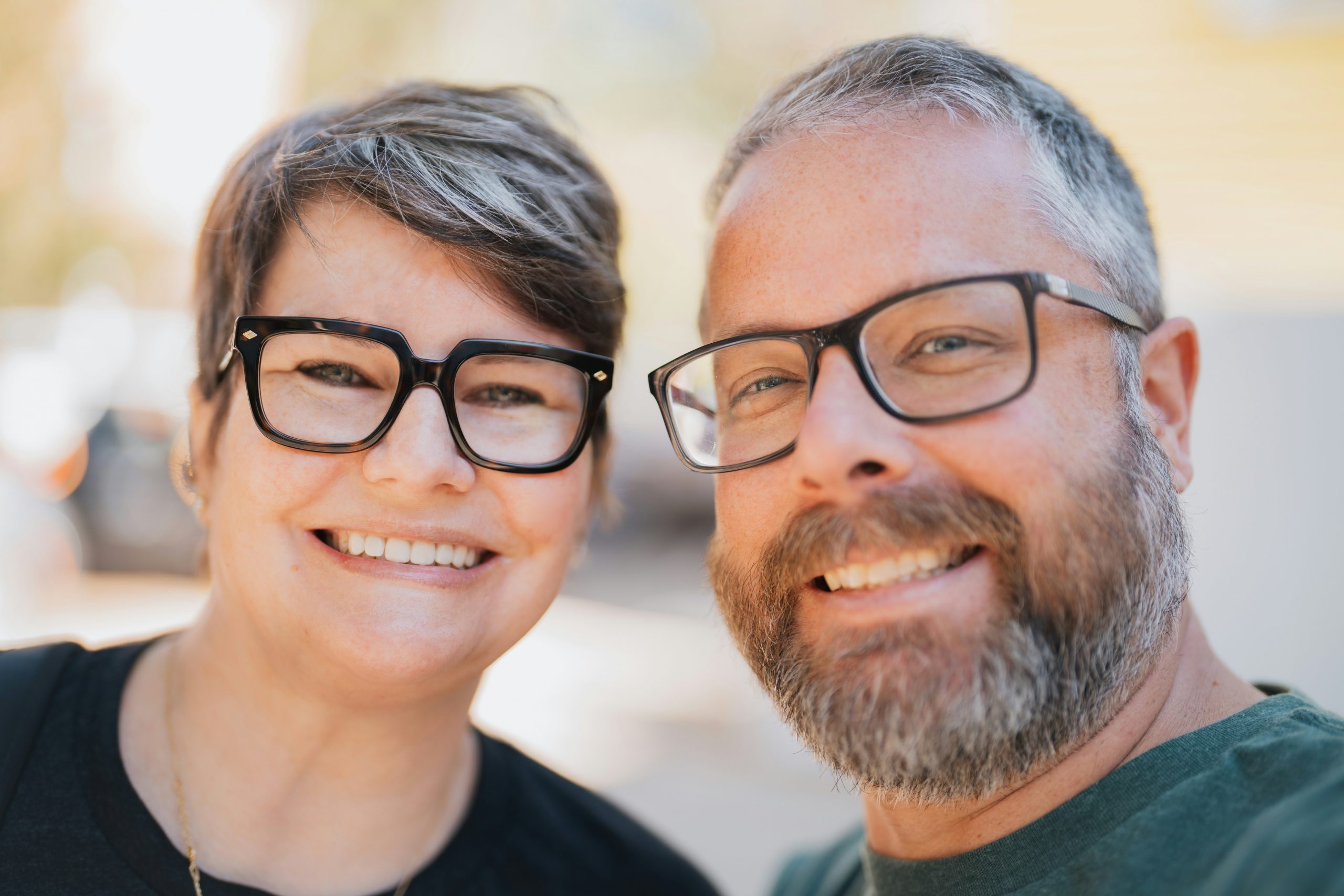 Couple (Man and Woman) smilling, looking happy, weaing glasses. Optical store. Prescription glasses.